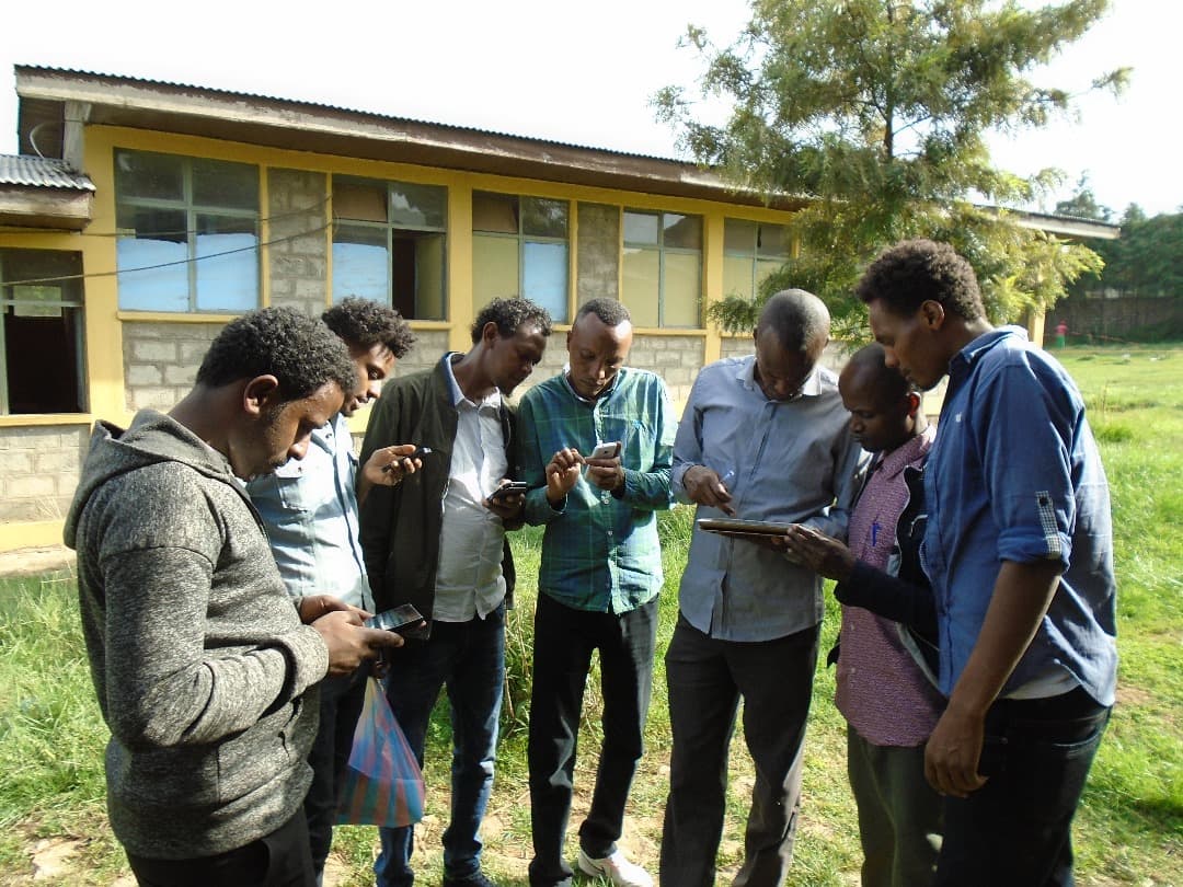 A group using phones and tablets together outside a school