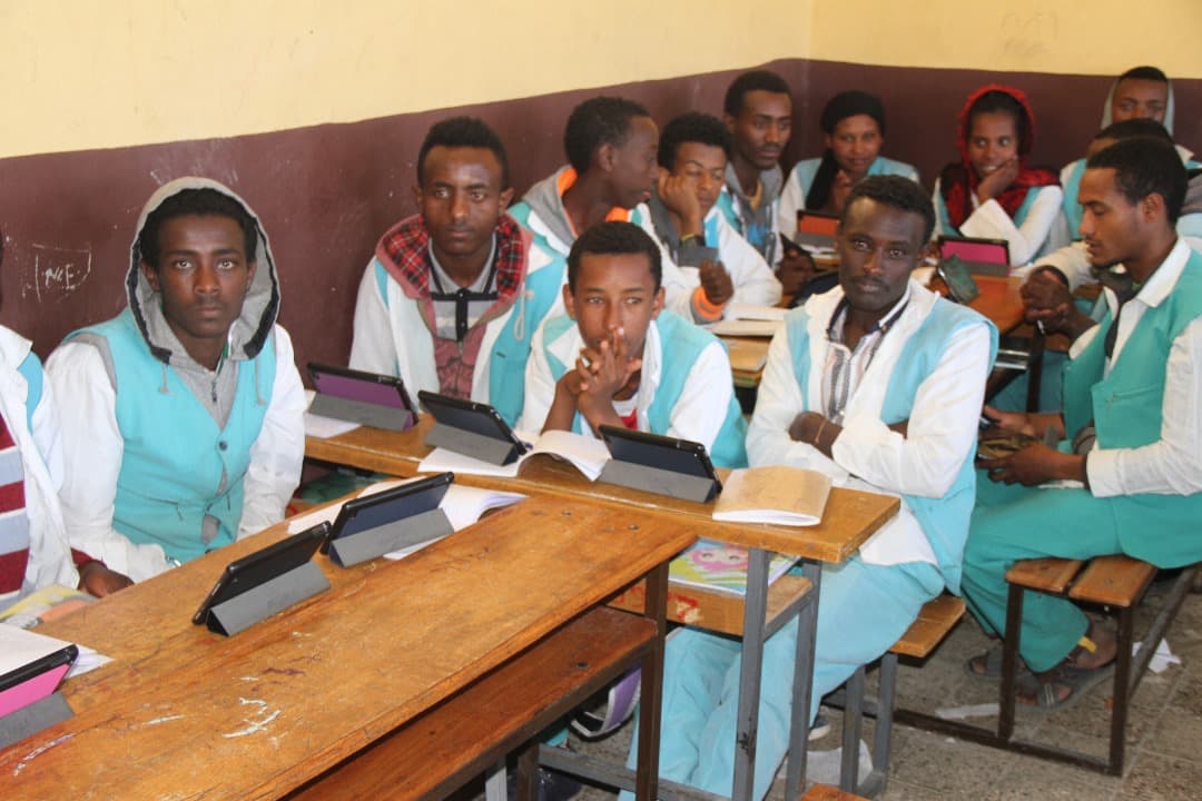 Students with tablets and books during a classroom lesson